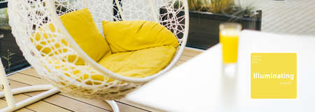 Hanging wicker chair, yellow cushions in minimalistic style outdoor interior. Demonstrating trendy Color of the Year 2021. Illuminating Yellow and Ultimate Gray. Duotone. Depression treatment. Bannerの写真素材
