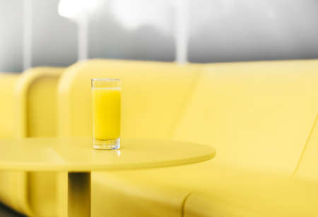 Bright yellow sofa, table against gray wall. Minimalistic style outdoor interior. Demonstrating trendy Color of the Year 2021. Illuminating Yellow and Ultimate Gray. Duotone. Depression treatmentの写真素材