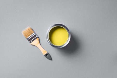 Open paint can with brush on grey background. Appartment renovation, repair, building, design concept. Demonstrating trendy Color of the Year 2021. Illuminating Yellow and Ultimate Gray. Duotoneの写真素材