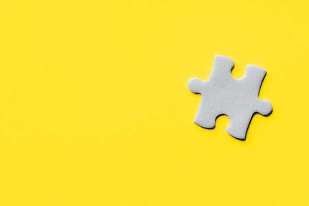 Closeup of jigsaw puzzle piece. Demonstrating trendy Color of Year 2021. Illuminating Yellow and Ultimate Gray. Duotone. Puzzle pieces on yellow background. idea, sign, symbol, concept of connectingの写真素材