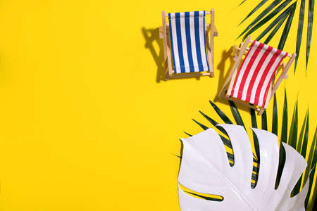 Flat lay of beach deck chairs, monstera and palm leaves on pink background with copy space. Summer and travel concept. Creative bannerの写真素材