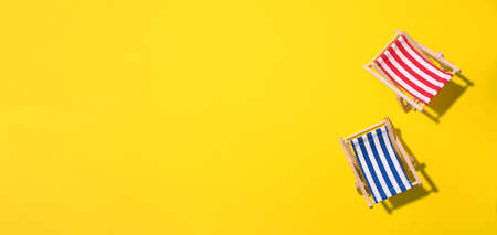 Deck chairs with hard shadow on yellow paper background. Flat lay and copy space. Summer travel vacation concept. Minimal compositionの写真素材