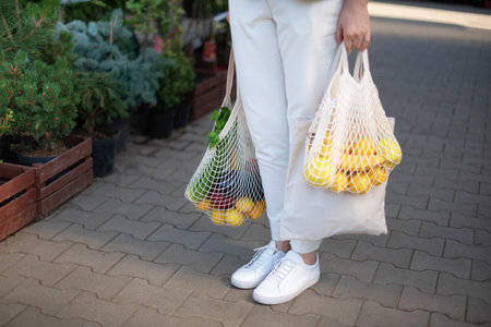 Zero waste concept with copy space. Woman holding cotton shopper and reusable mesh shopping bags with vegetables, products. Eco friendly mesh shopper. Zero waste, plastic free concept.の写真素材