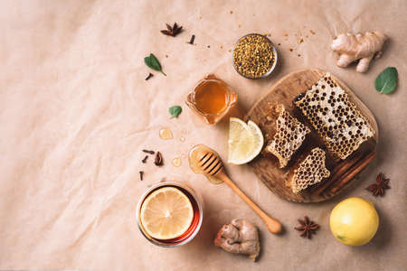 Alternative medicine concept. Ingredients for flu fighting natural hot drink. Copy space. Top view. Lemon, ginger, mint, honey, apple and spices on craft paper backgroundの写真素材