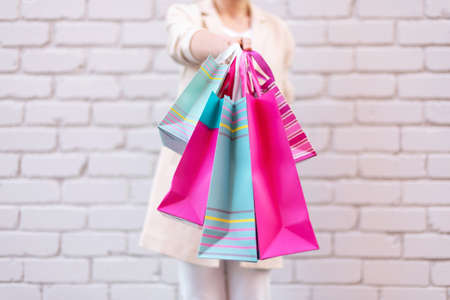 Shopping concept. Girl holding bunch of shopping bags with purchases near brick background. Copy space. Sale, discount, black friday concept. Shopping mall and outletの写真素材