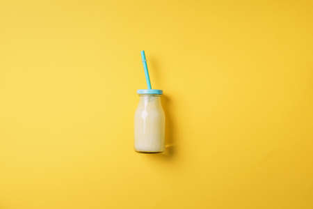 Bottles of orange, white, pink smoothie with straws on yellow background. Top view. Flat lay. Copy space. Detox summer drink. Healthy fresh juice bottle. Vegan and vegetarian concept.の写真素材