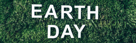 Inscription Earth Day. Biophilia concept. Nature backdrop. Word Earth Day on moss, green grass background. Top view. Copy space. Banner. April 2. Save planet from environmental pollutionの写真素材