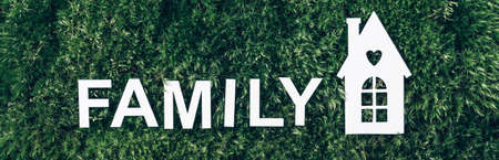 Family concept. White home icon, inscription family on green grass field, moss background. Top view. Copy space. Banner. Biophilia concept. Nature concept, eco friendly lifestyleの写真素材