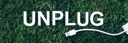 Word Unplug, white internet usb adapter on moss, green grass background. Top view. Copy space. Banner. Biophilia concept. Nature backdropの写真素材