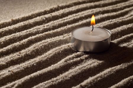 Lit Tea Candle on White Sand in Abstract Lightingの写真素材