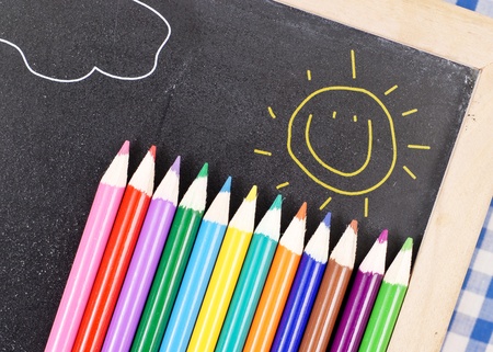 Colored Pencils on Chalk Board with Happy Sun Drawingの写真素材