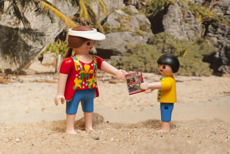Playmobil toy breast and son on the beach sharing a book