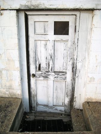 An old white beaten up doorway with paint chipping off.の写真素材