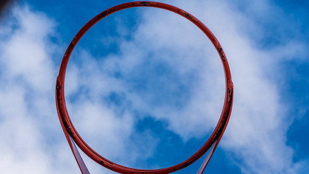Upwards view of basketball hoop against a bright blue skyの写真素材