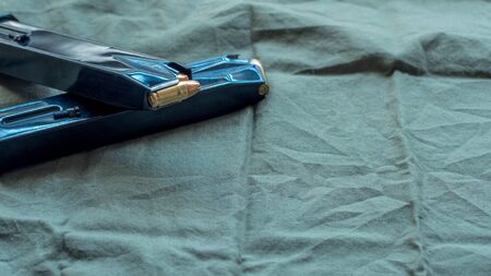 Black steel handgun pistol magazines loaded with hollow point ammunition, resting on an olive drab...