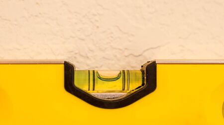 Yellow bubble level showing bubble in the level position to indicate a flat plane, resting against a...