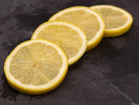 Four slices of lemon on slate wet stoneの写真素材