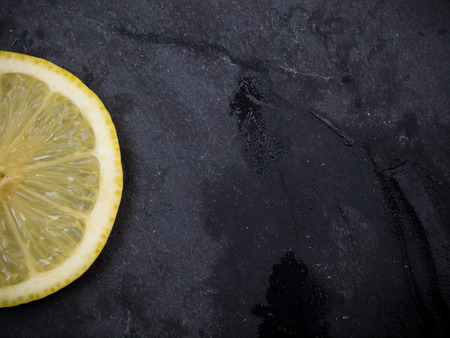 One slice of lemon on slate wet stone with spaceの写真素材