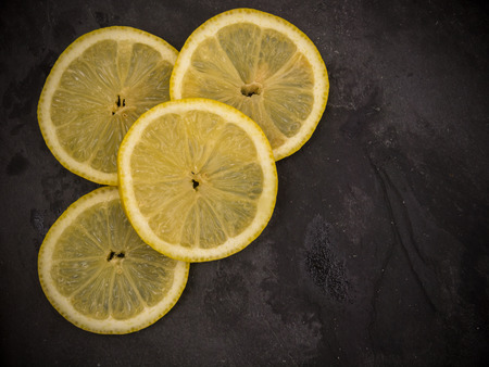Four slices of lemon on slate wet stoneの写真素材