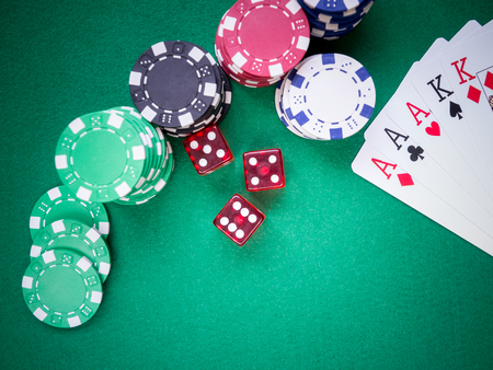 poker full house of aces and kings on green table with red covers and poker chipsの写真素材