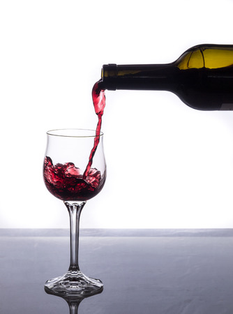 serving a glass of red wine on a gray table with white backgroundの写真素材