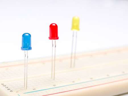 three color leds in breadboard isolated in white background. Close up. Selective focus.