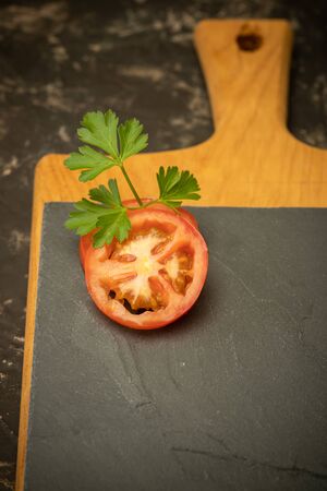 two tomato slices with parsley on black stone and cutting board. Food background
の写真素材