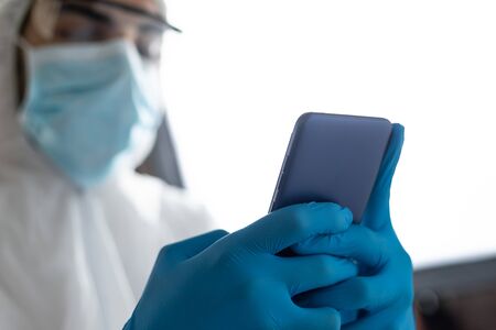 doctor with protective clothing for covid-19 watching the mobile phone in the operating room