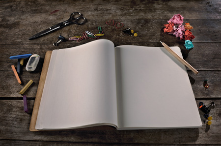 Blank notebook with pencil, paper clips, and other office supplies  chalk pastels, eraser, scissor, thumbtacks   It can be easily customized with any text の写真素材