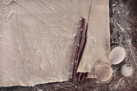 Vintage cooking setup, homemade baking dough and ingredients  cinnamon sticks, brown and white sugar, an egg  over a retro wooden table の写真素材