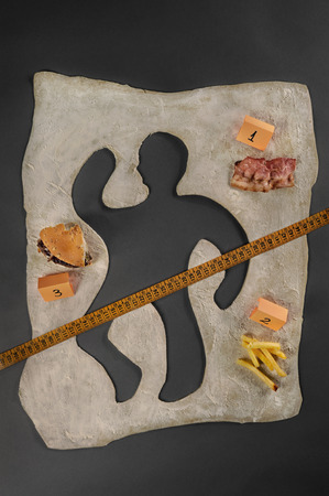 Unhealthy food victim  Crime scene, a silhouette of a man made out of baking dough  Next to the victim s silhouette there are several evidences about the cause of death, a piece of bacon, a hamburger, fries, a measuring tape の写真素材
