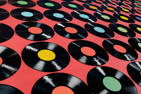 Music - Vinyl records  Colorful collection of vinyl records, LPs, on red background, angle view  The labels can be easily customized, the image is suitable for background use  の写真素材