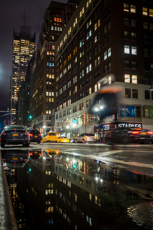 NEW YORK, USA - FEBRUARY 22, 2018: Cyclist riding at night in the streets of Time Square in New York in the rainのeditorial素材