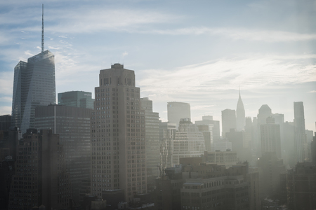 Blue sunrise with dazzling sun rays over New York from a high floor of a building in downtown Manhattanの写真素材