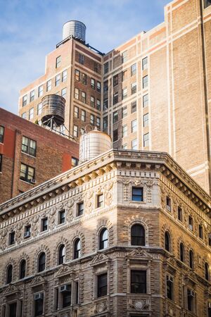 Water towers over buildings of different eras in New York on a sunny day