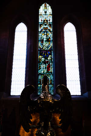 Bronze eagle statue in front of stained glass windows inside a church in Rome, Italyのeditorial素材