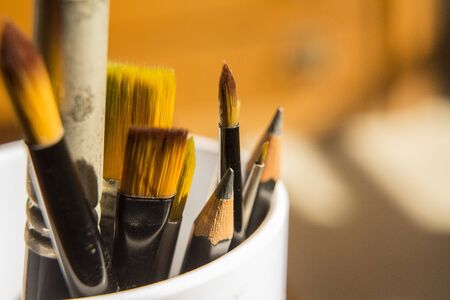 close up brushes and pencils for art background orange