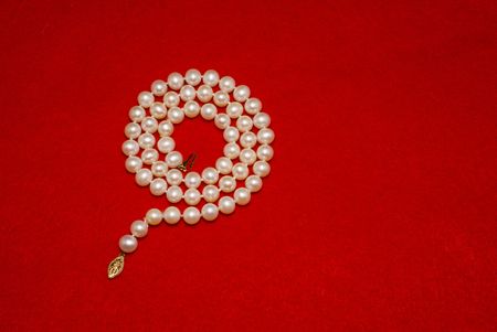 A beautiful question mark shaped pearl Necklace on a red felt backgroundの写真素材
