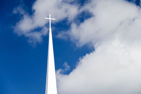 A white church steeple with cross on top and blue skyの写真素材