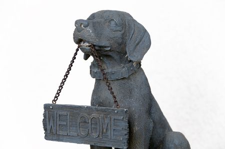Stone statue of a dog holding a welcome sign on chainsの写真素材