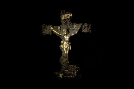 Gold statue of Jesus crucified on lava rock with black backgroundの写真素材