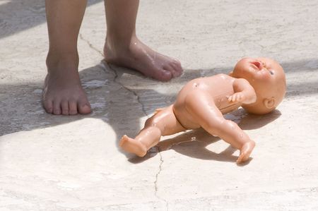 Dropped wet blue eyed baby doll by a toddlerの写真素材