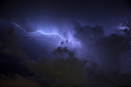 Blue Lightning strike surrounded by storm clouds and rain columnsの写真素材