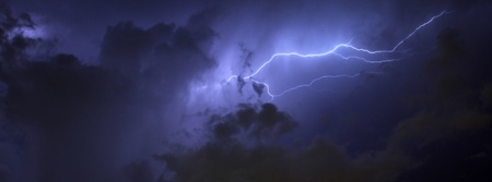 Blue Lightning strike surrounded by storm clouds and rain columns in banner formatの写真素材