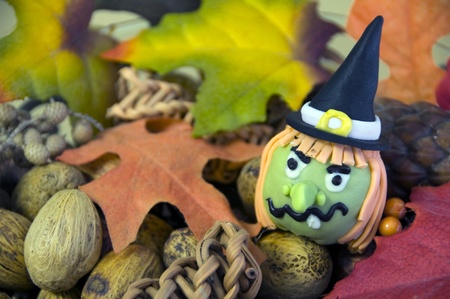 Colorful green and orange halloween witch cake pop covered with icing filled with pastry in an autumn potpourri bed of acorns leaves and nutsの写真素材