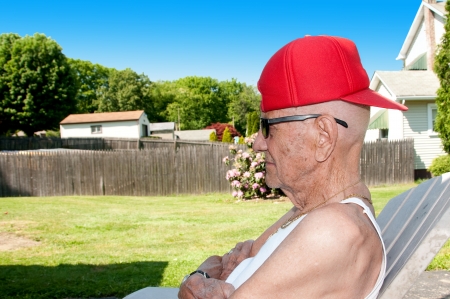 Older man with red hat turned backwards and sunglasses showing a bit of attitudeの写真素材