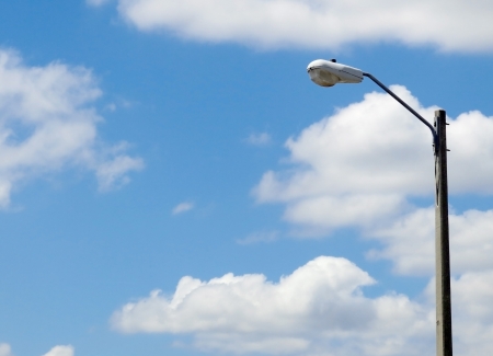 Street light mounted on a concrete pole with partly cloudy blue sky         の写真素材