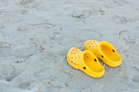 Bright yellow flip-flops on sand beach