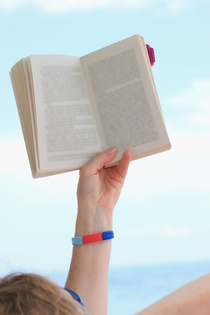 hand holding book over blue skyの写真素材