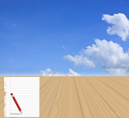 Torn grid paper and pencil on wood floor with a blue sky backgroundの写真素材